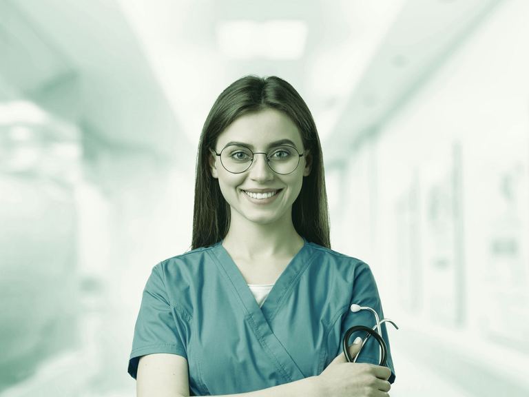 A smiling travel nurse in navy scrubs walking through a bright terminal with a rolling suitcase
